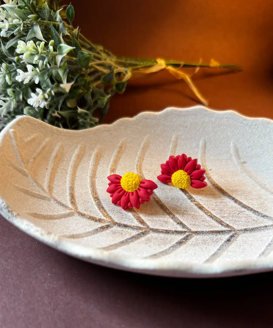 Cercei handmade din lut polimeric în formă de floare stilizată, petale roșii cu centru galben texturat prezentare forma frunza